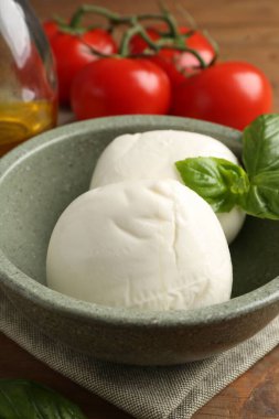 Lezzetli mozarella topları, domatesler ve fesleğenler ahşap masada, yakın plan.