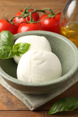 Lezzetli mozarella topları, domatesler ve fesleğenler ahşap masada, yakın plan.