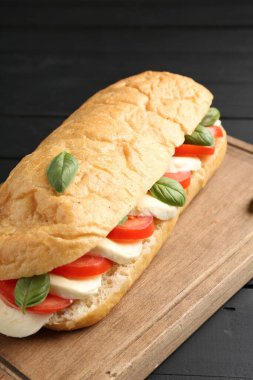 Mozarella peynirli, domatesli, fesleğenli, siyah ahşap masa, yakın plan.