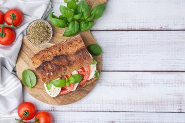 Mozarella peynirli, domatesli, fesleğenli, beyaz ahşap masa, düz yatak. Metin için boşluk