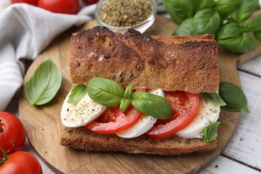 Mozarella peynirli, domatesli, fesleğenli, beyaz ahşap masa, yakın plan.