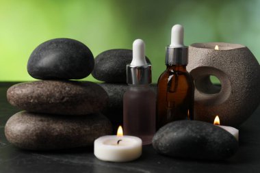 Taşlar, damlalar ve yanan mumlar ile kaplıca bileşimi koyu yeşil arka planda, yakın plan