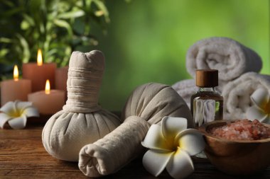 Bitkisel poşetler ve kozmetik ürünlerle kaplıca bileşimi ahşap masa üzerinde bulanık yeşil arka plan, yakın çekim