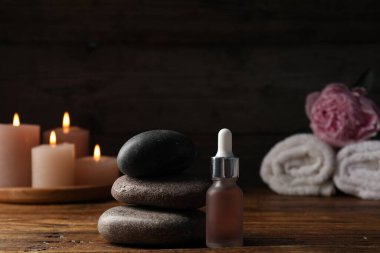 Siyah arkaplana karşı ahşap masa üzerinde taş yığını ve damlatıcıyla kaplıca bileşimi, yakın plan