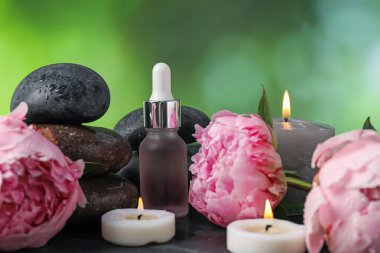 Bulanık yeşil arka planda ıslak taşlar, damlalar ve çiçekli spa kompozisyonu