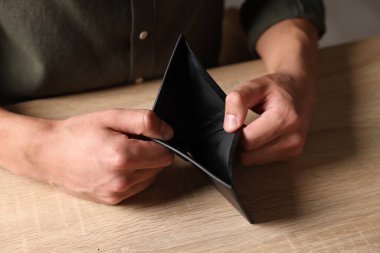 Ahşap masada cüzdanı boş bir adam, yakın plan.