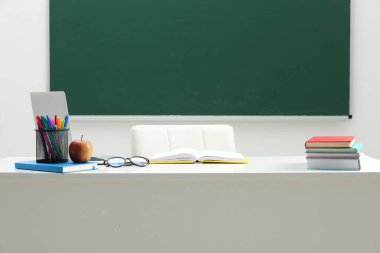 Farklı okul kırtasiyesi, bardaklar ve elma beyaz masada, kapalı alanda.