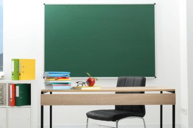 Farklı kitaplar, gözlük ve kırmızı elma, kapalı alanda, tahtanın yanında.