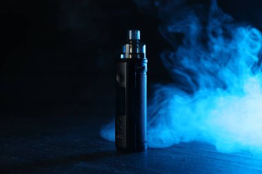 Siyah masada mavi ışıkta elektronik sigara içen cihaz