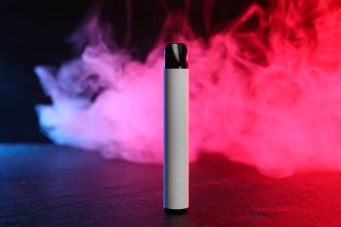 Siyah masada kırmızı ışıkta elektronik sigara içen cihaz