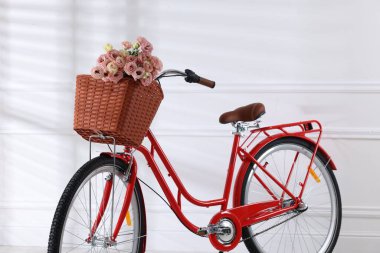 Beyaz duvarın yanında bir sepet güzel çiçekli bisiklet.