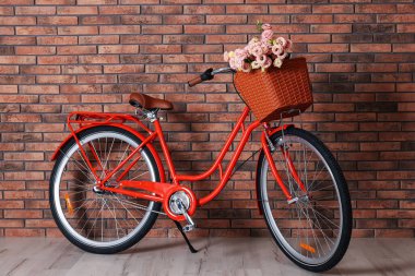 Evin içinde tuğla duvarın yanında bir sepet güzel çiçekli bisiklet.