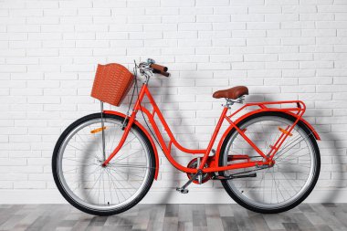 Beyaz tuğla duvarın yanında sepeti olan kırmızı bisiklet.