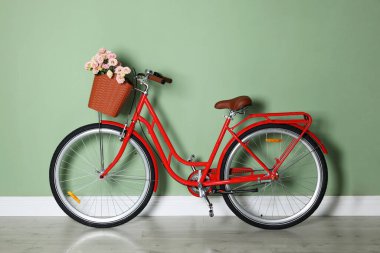 Açık yeşil duvarın yanında bir sepet güzel çiçekli bisiklet.