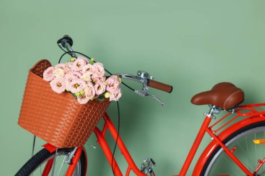 Açık yeşil duvarın yanında güzel çiçeklerle dolu bisiklet, yakın plan.