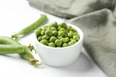 Taze taze bezelyeler beyaz ahşap masada, yakın plan.