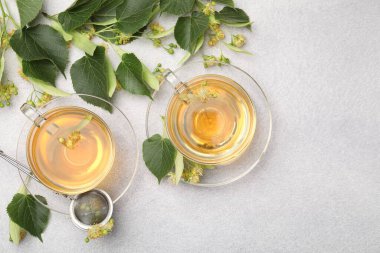 Taze ıhlamur çayı fincanda ve çiçekler açık gri masada, düz yerde. Metin için boşluk