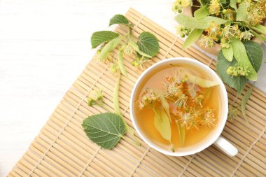 Taze ıhlamur çayı fincanda ve beyaz ahşap masada çiçekler düz yerde. Metin için boşluk