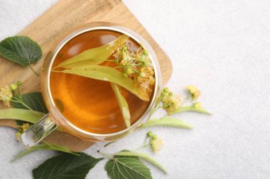 Taze ıhlamur çayı fincanda ve çiçekler açık gri masada, düz yerde. Metin için boşluk