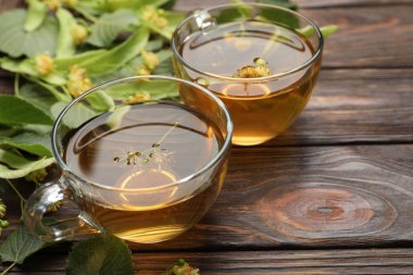 Fincanlarda taze ıhlamur çayı ve ahşap masada çiçekler, yakın plan. Metin için boşluk