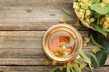 Fincanda nefis ıhlamur çayı, ahşap masada yapraklar ve çiçekler, düz uzanma. Metin için boşluk