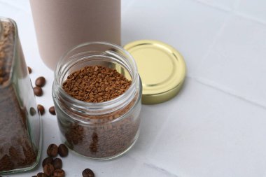 Kavanozlarda kahve ve beyaz fayanslı masada fasulye, yakın plan. Metin için boşluk