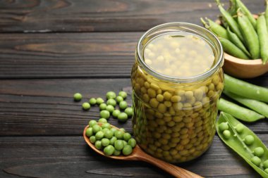 Kavanozda bezelye turşusu ve siyah ahşap masada kabuklar, yakın plan. Metin için boşluk