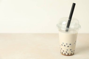 Bej masadaki plastik bardakta lezzetli sütlü çay, metin için yer.