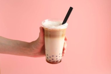 Pembe arka planda lezzetli sütlü çay içen kadın, yakın plan.