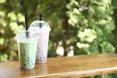 Tahta masada plastik bardakta lezzetli sütlü çay. Metin için boşluk