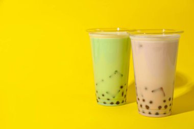 Sarı arka planda plastik bardakta lezzetli sütlü çay. Metin için boşluk