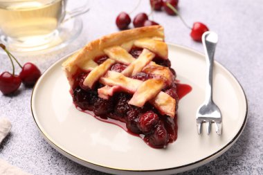 Lezzetli vişneli turta, böğürtlen ve çatal gri desenli masa, yakın plan.