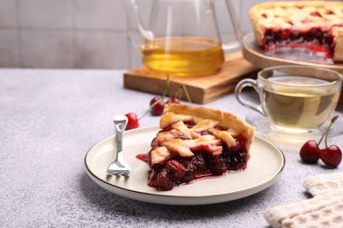 Lezzetli vişneli turta, gri desenli masa üzerindeki çilek ve çay fayanslı duvara yakın çekim.
