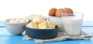 Farklı süt ürünleri ve yumurtalar mavi ahşap masada beyaz arka planda