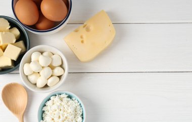 Farklı süt ürünleri ve yumurtalar beyaz ahşap masada, düz yerde. Metin için boşluk