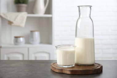 Süt ürünleri. Bardaktaki taze süt ve içerideki gri desenli masada duran şişe. Metin için boşluk