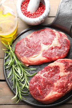 Ahşap masanın üstünde çiğ et ve baharat parçaları.