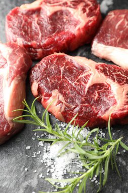 Çiğ et parçaları ve baharatlar karanlık masada, yakın plan.