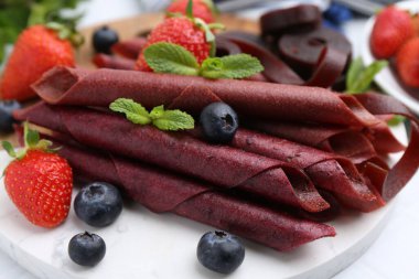 Lezzetli meyve dürümleri, çilekler, yaban mersini ve nane şekeri beyaz masada, yakın plan.