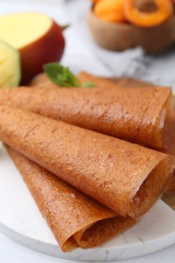 Lezzetli meyve dürümleri, nane, mango ve kayısılar masada, yakın plan.