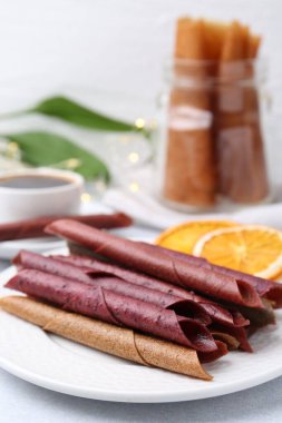 Lezzetli meyve dürümleri ve portakal dilimleri beyaz masada, yakın plan.