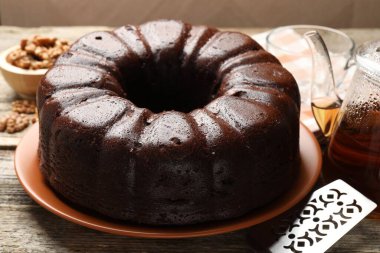 Lezzetli çikolatalı kek, sunucu, ceviz ve çay ahşap masada, yakın plan.