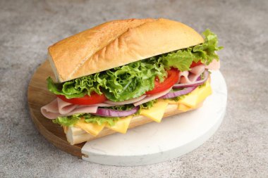 Jambonlu, peynirli ve sebzeli baget sandviç. Gri dokulu masa, yakın plan.