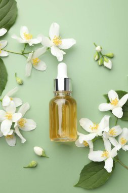 Yağ ve yasemin çiçekleri yeşil arka planda düzdür.