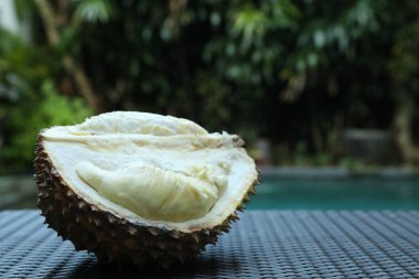 Açık havuz kenarındaki hasır masada taze olgun durian, yakın plan. Metin için boşluk