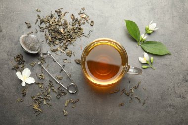 Cam bardakta Aromatik yasemin çayı, Gri masada bira ve çiçekler, düz uzanmış