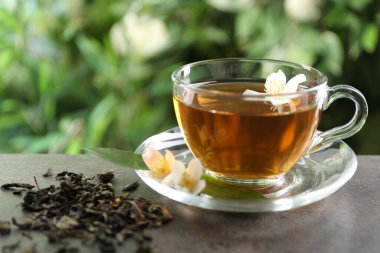 Aromatik yasemin çayı cam bardakta, bira ve çiçekler açık havada, yakın plan.