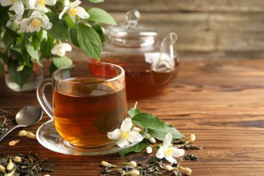 Cam bardakta Aromatik yasemin çayı, çaydanlık, ahşap masada demlik ve çiçekler, yakın plan. Metin için boşluk