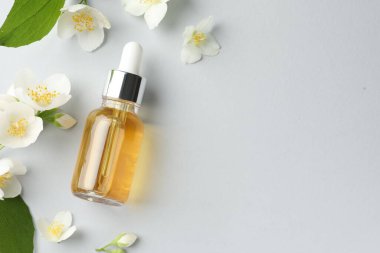 Kozmetik ürünleri ve yasemin çiçekleri arka planda, düz yerde. Metin için boşluk