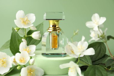 Yeşil arka planda bir şişe parfüm ve yasemin çiçeği, yakın plan.